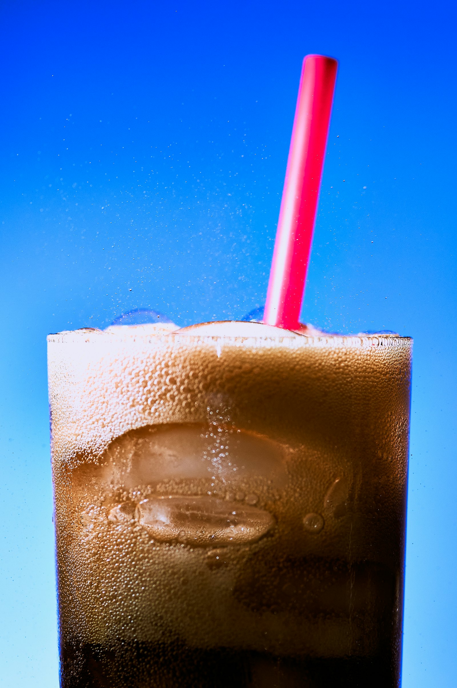 A soda float with a bright red straw against a blue sky